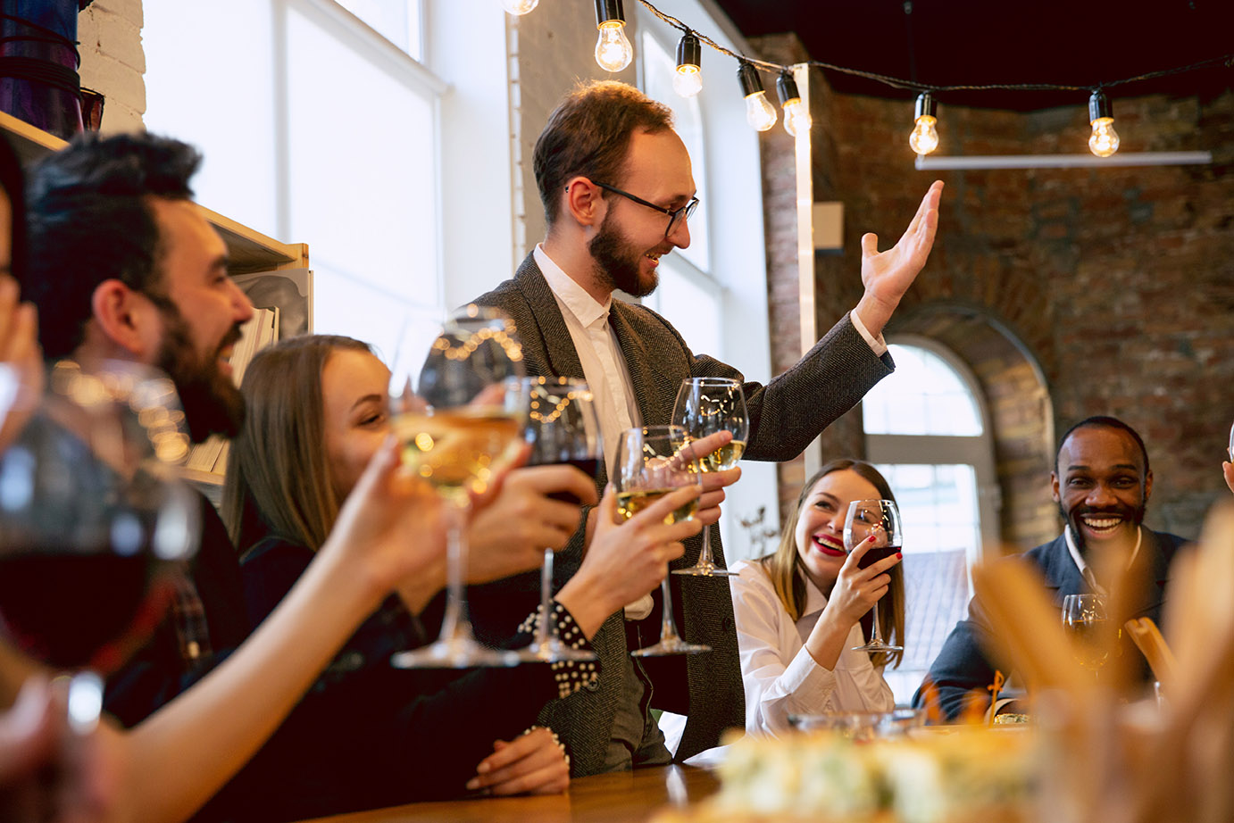 Happy co-workers celebrating while company party and corporate event. Young caucasian people in business attire cheering, laughting. Concept of office culture, teamwork, friendship, holidays, weekend.