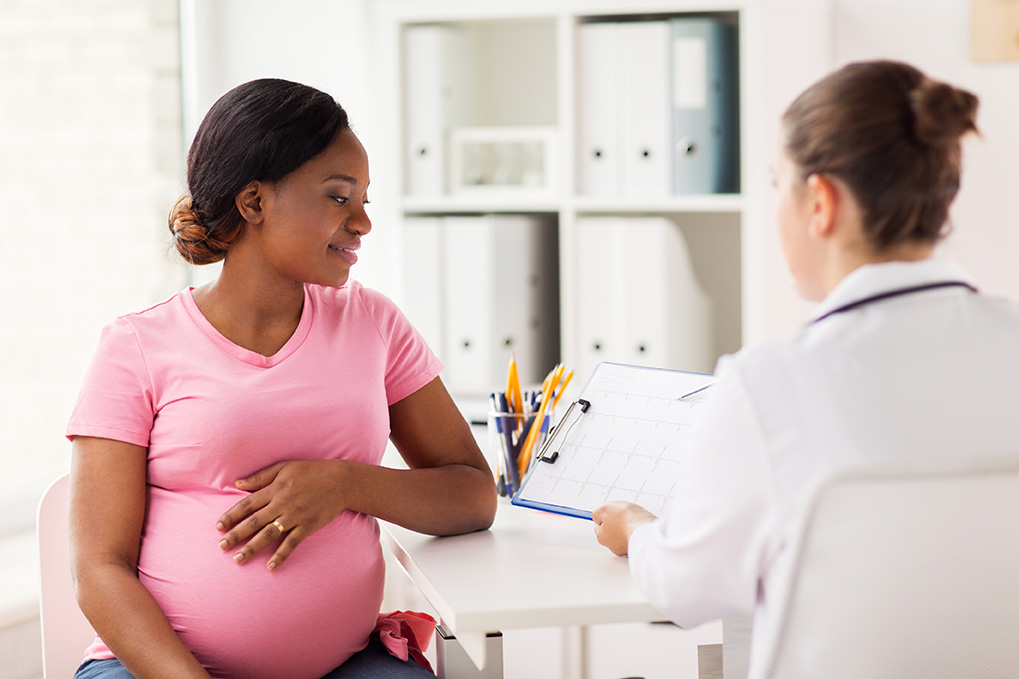 pregnancy, medicine, healthcare and people concept - cardiologist doctor showing cardiogram to pregnant african american woman meeting at hospital