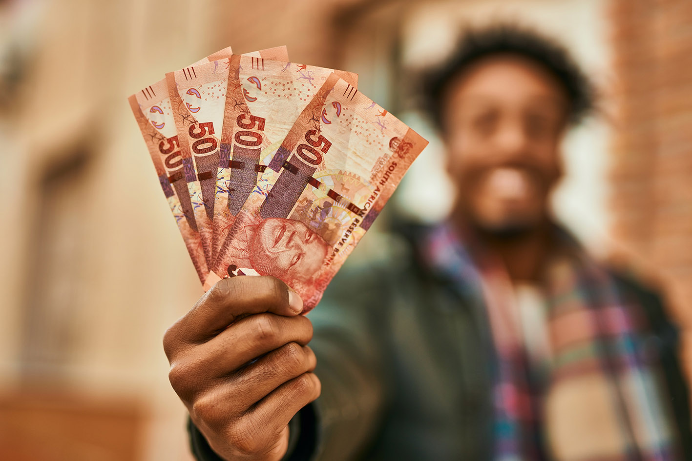 Young african american man smiling happy  holding south africa rands banknotes at the city